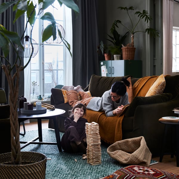 A mother on a FÄRLÖV sofa and a child on the floor play together. GRINDFALLET pendant lamps hang from the ceiling.