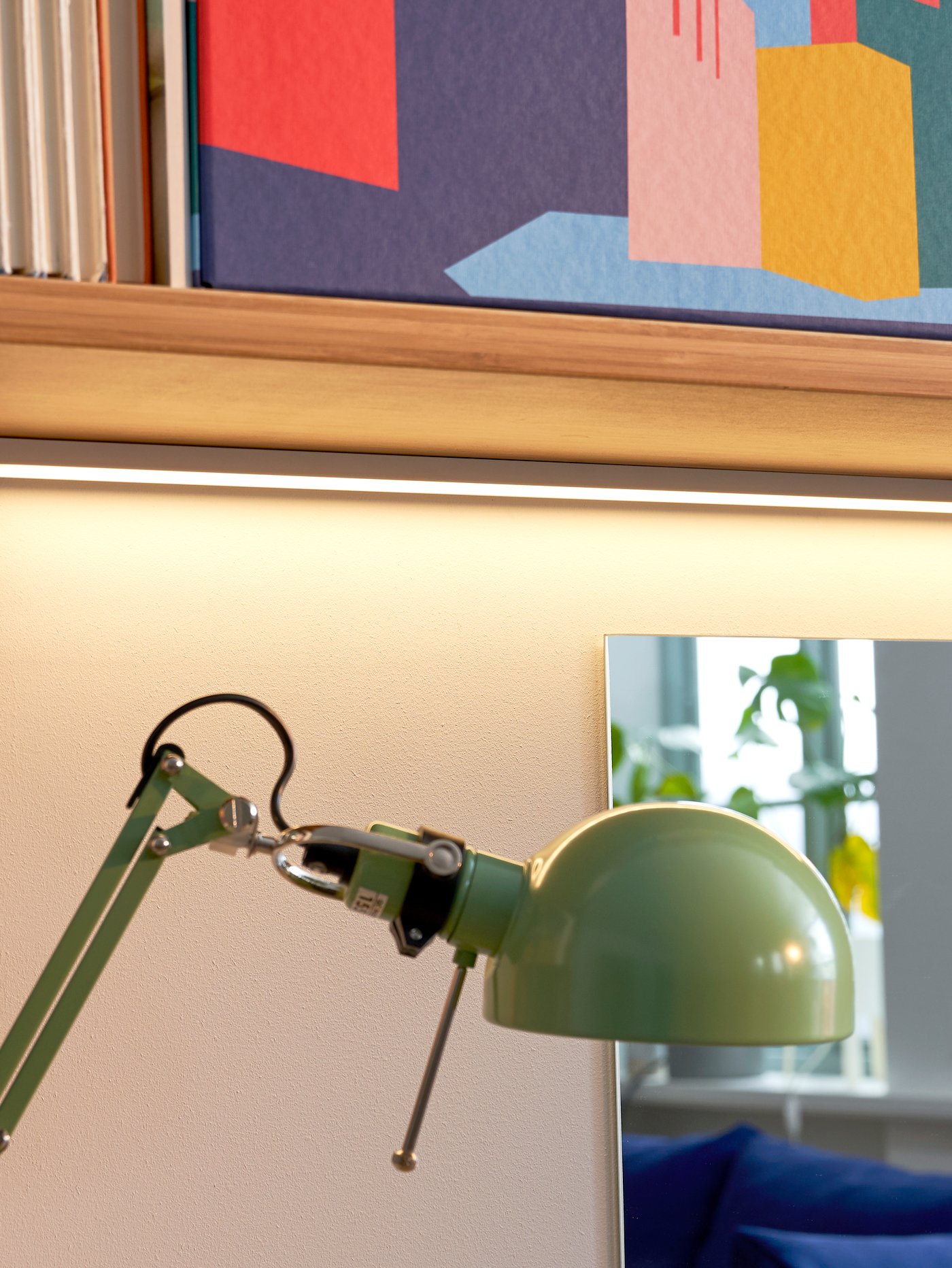 Green LED worktop lighting, with a mirror behind reflecting the room and a shelf above with a colourful storage box.