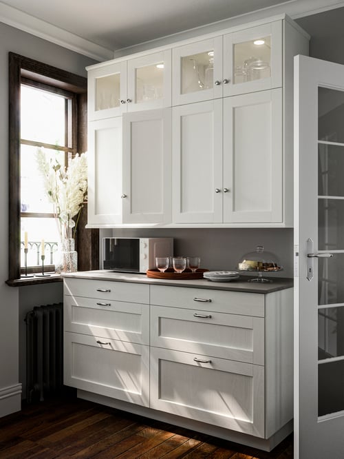 Cuisine moderne dotée d’une armoire murale à deux portes, de deux petites portes vitrées, d’un plateau brun et d’un plateau de service.