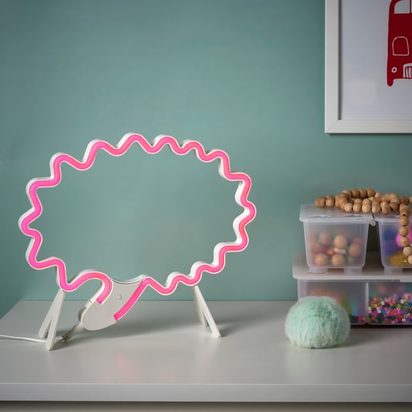 A pink light on a white surface next to a group of plastic containers.