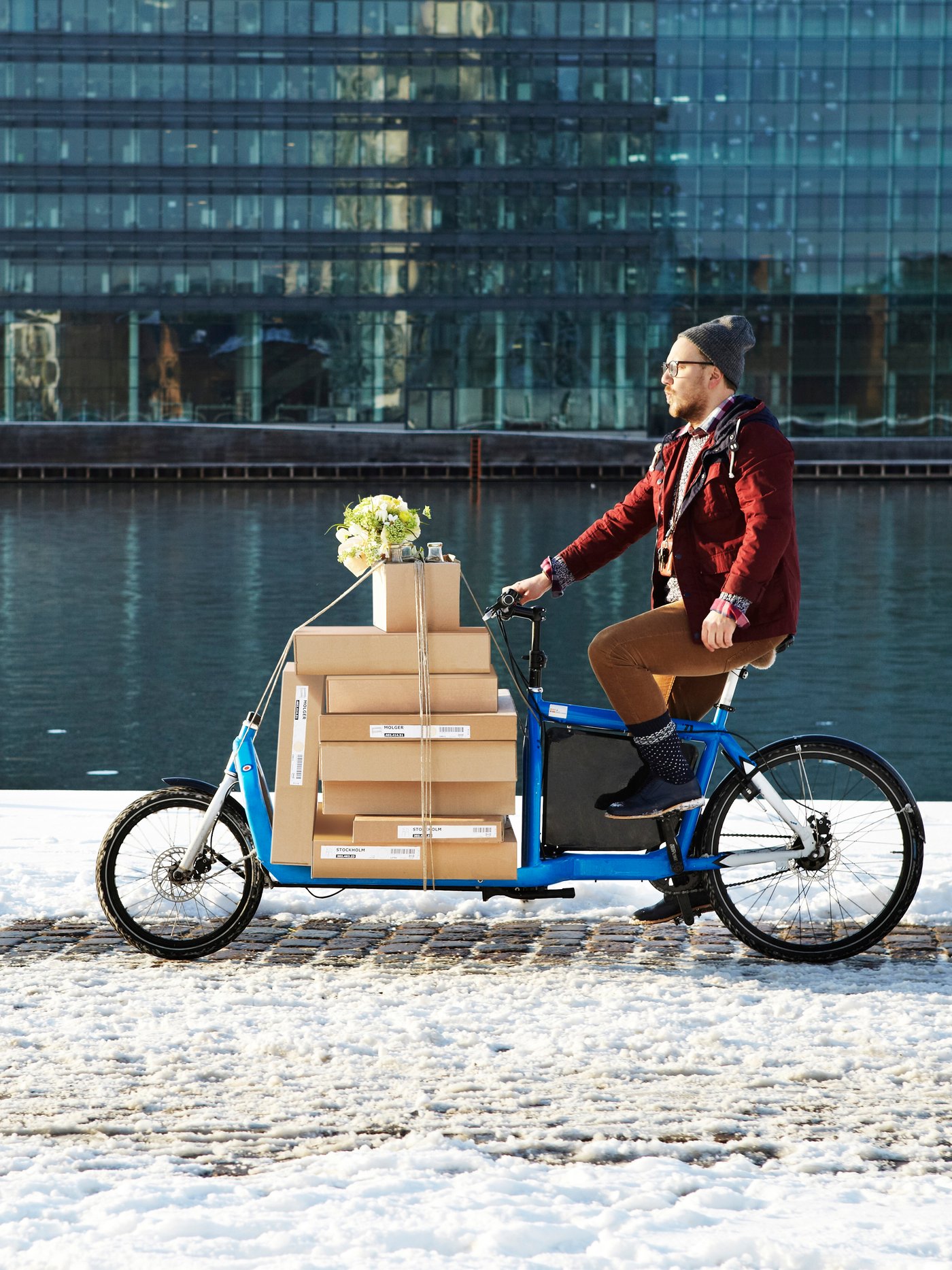 Eine Person fährt ein Lastenfahrrad beladen mit IKEA Paketen.