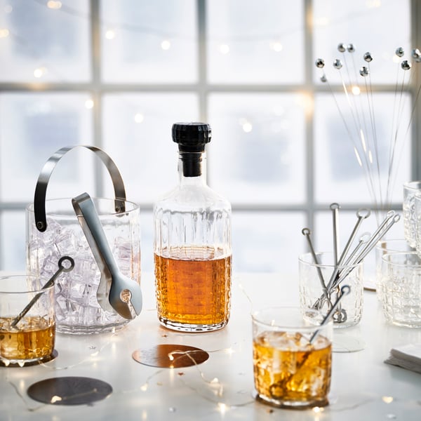 A clear glass/stainless steel FRÖJDA ice bucket with tongs