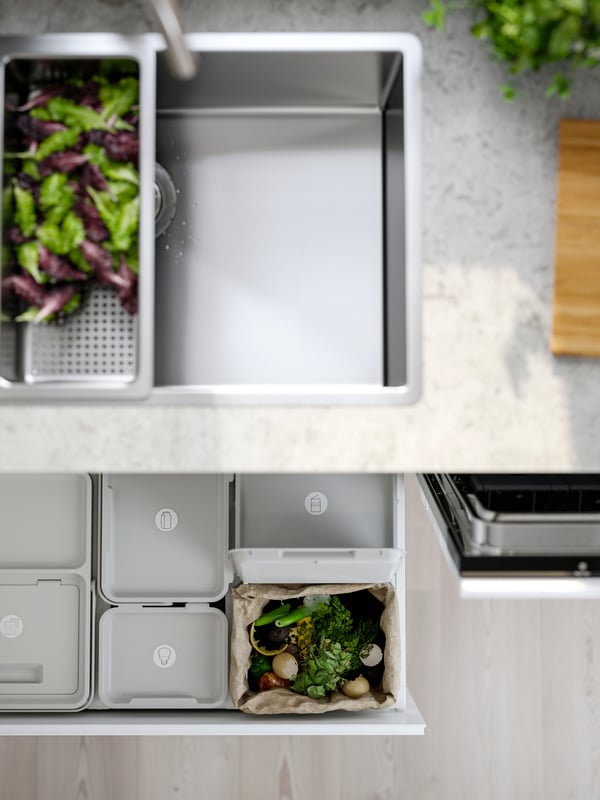 A VRESJÖN inset sink with one bowl has a colander with lettuce in it and waste sorting bins can be seen in the drawer below.