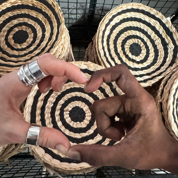 Two hands of people with different skin colours form a heart in front of piles of MÄVINN wall decoration.