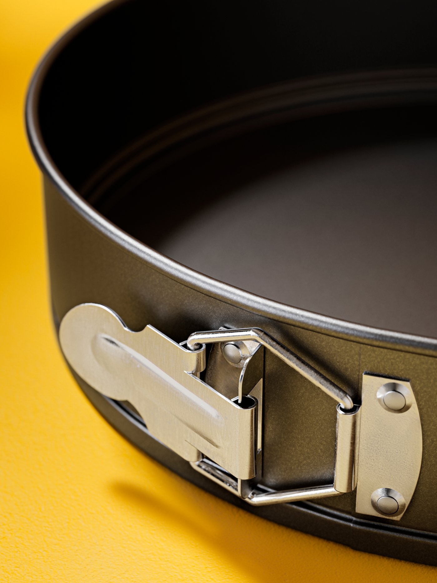 Del temno sivega MÅNTAGG pekača s snemljivim obodom z oblogo proti prijemanju, kjer je mehanizem za zaklepanje z zaponko.