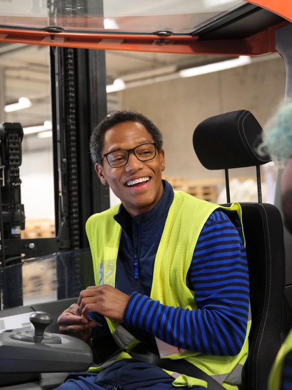 A co-worker in a forklift talking to a colleague.