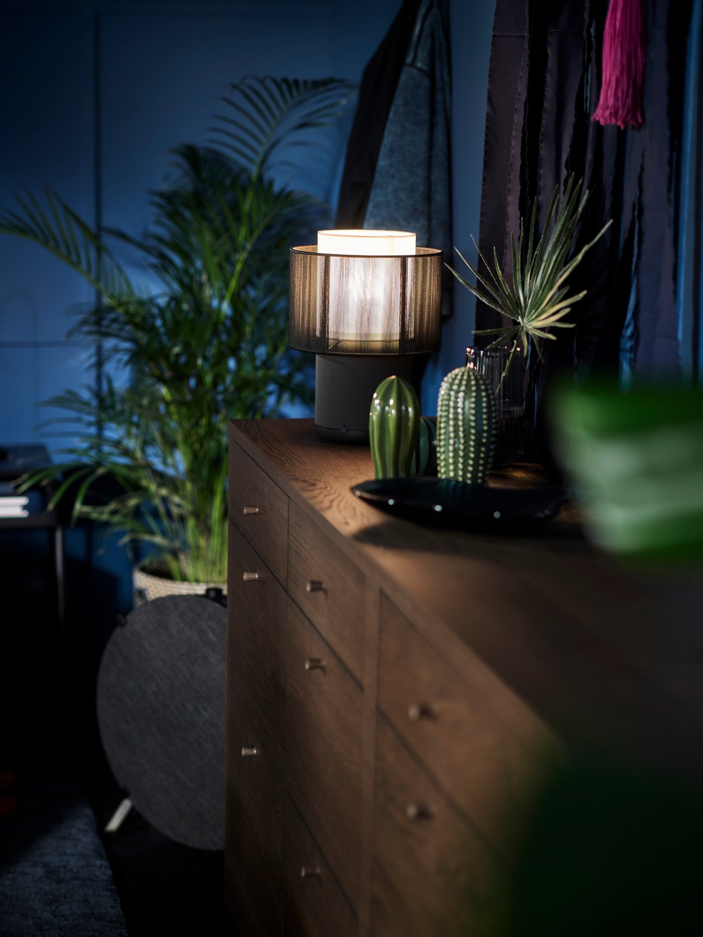 A black STARKVIND air purifier by two TONSTAD chests with 6 drawers. One chest has a SYMFONISK speaker lamp with WiFi on it.