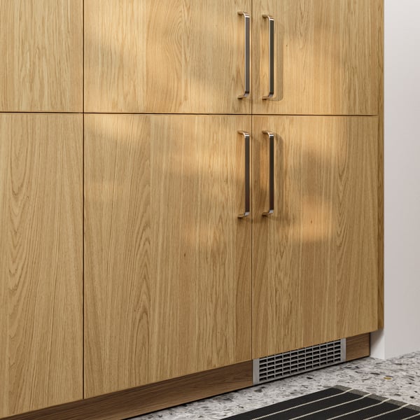 A closeup of SEKTION cabinets with fronts in SINARP oak veneer with stainless steel-coloured KALERUM handles.