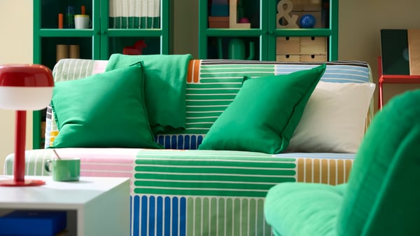 Un sofá LYCKSELE con una funda colorida con diferentes patrones en verde.
