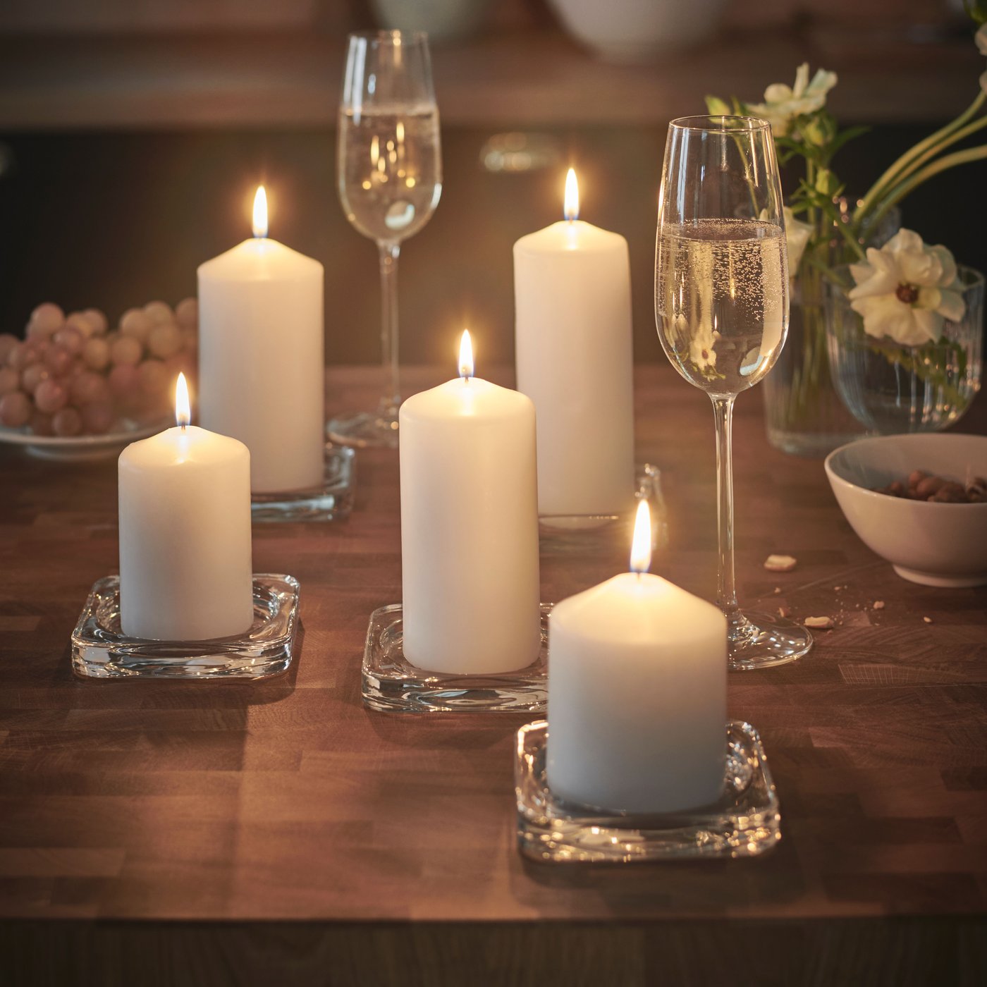 Tummalla sohvapöydällä on viisi valkoista FENOMEN-pöytäkynttilää, joissa palaa liekki.