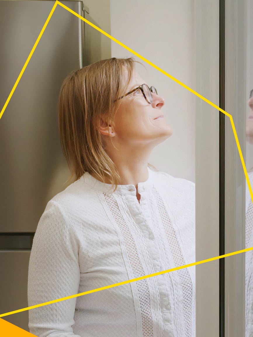 Woman looking out of the window of her home.