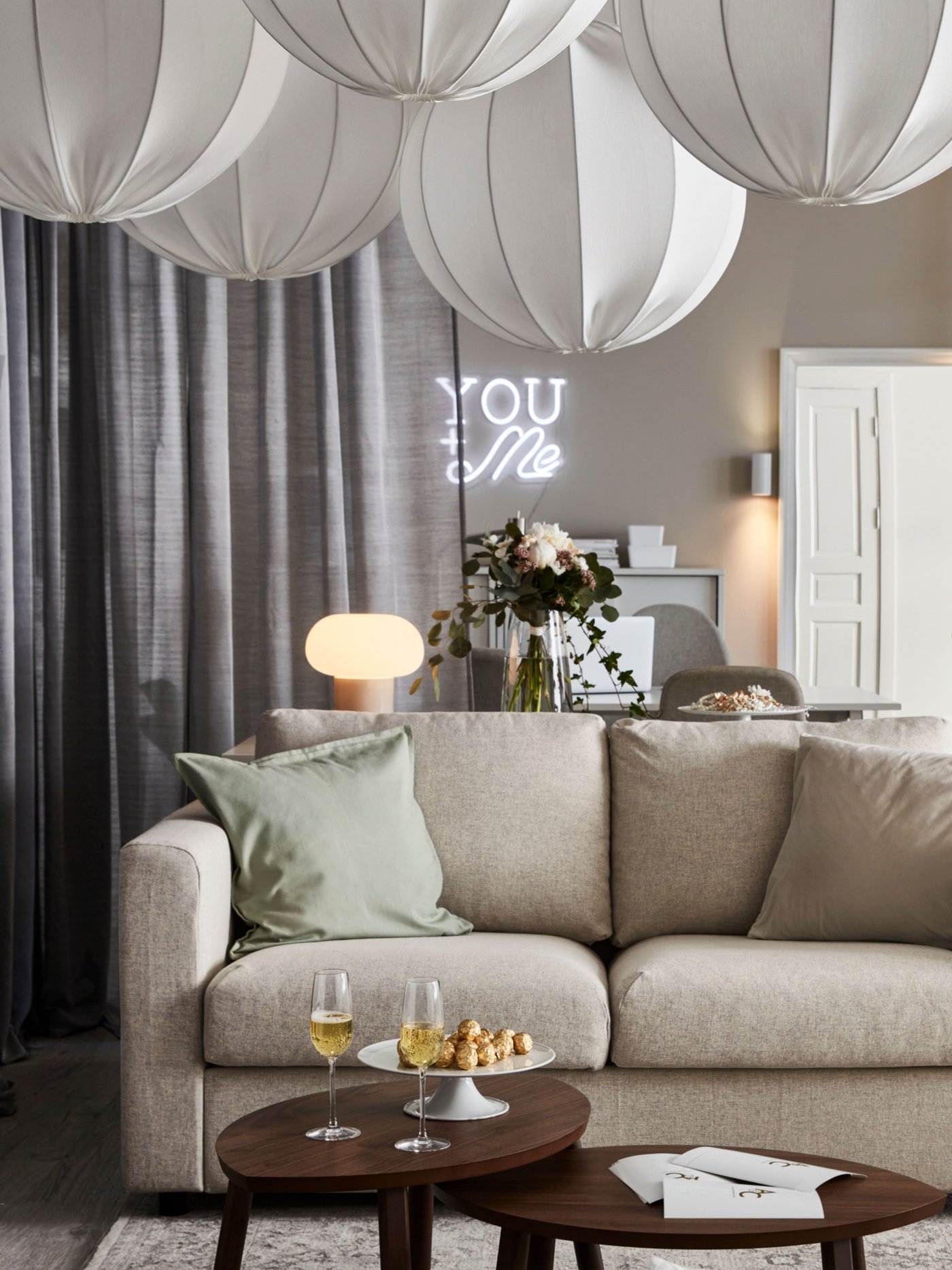 Fünf REGNSKUR/SUNNEBY Pendelleuchten hängen von der Decke über einem beigen VIMLE Sofa und einem STOCKHOLM Satztisch-Set mit zwei Tischen.