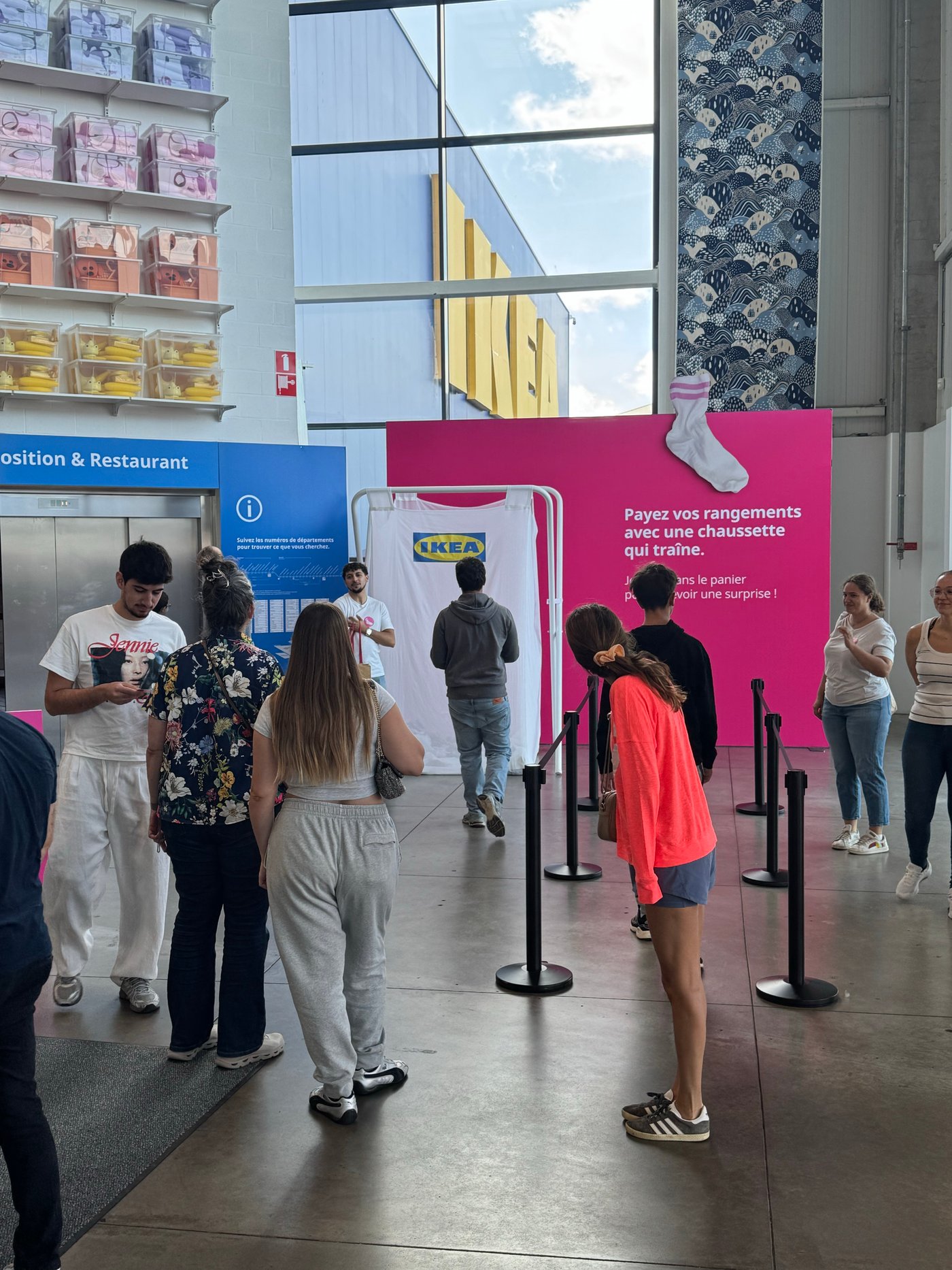 Bezoekers verzamelen zich rond een IKEA-activatie met een roze wand en doelshirt in de open winkelomgeving.