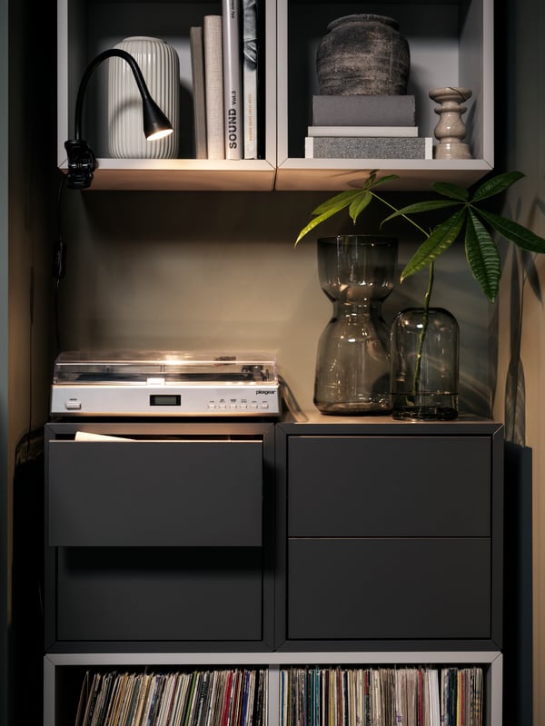 A wall section with records in light-grey EKET shelving units and dark-grey cabinets with drawers with a record player atop.