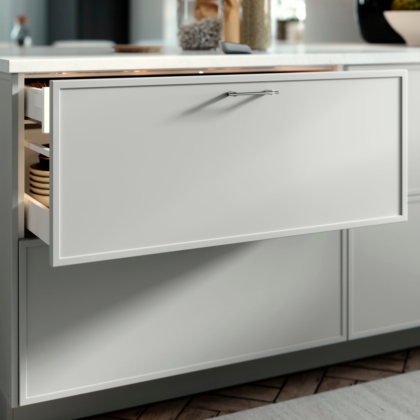 SEKTION kitchen drawer with an ASPUDDEN drawers front in light gray, opened slightly showing bowls inside.