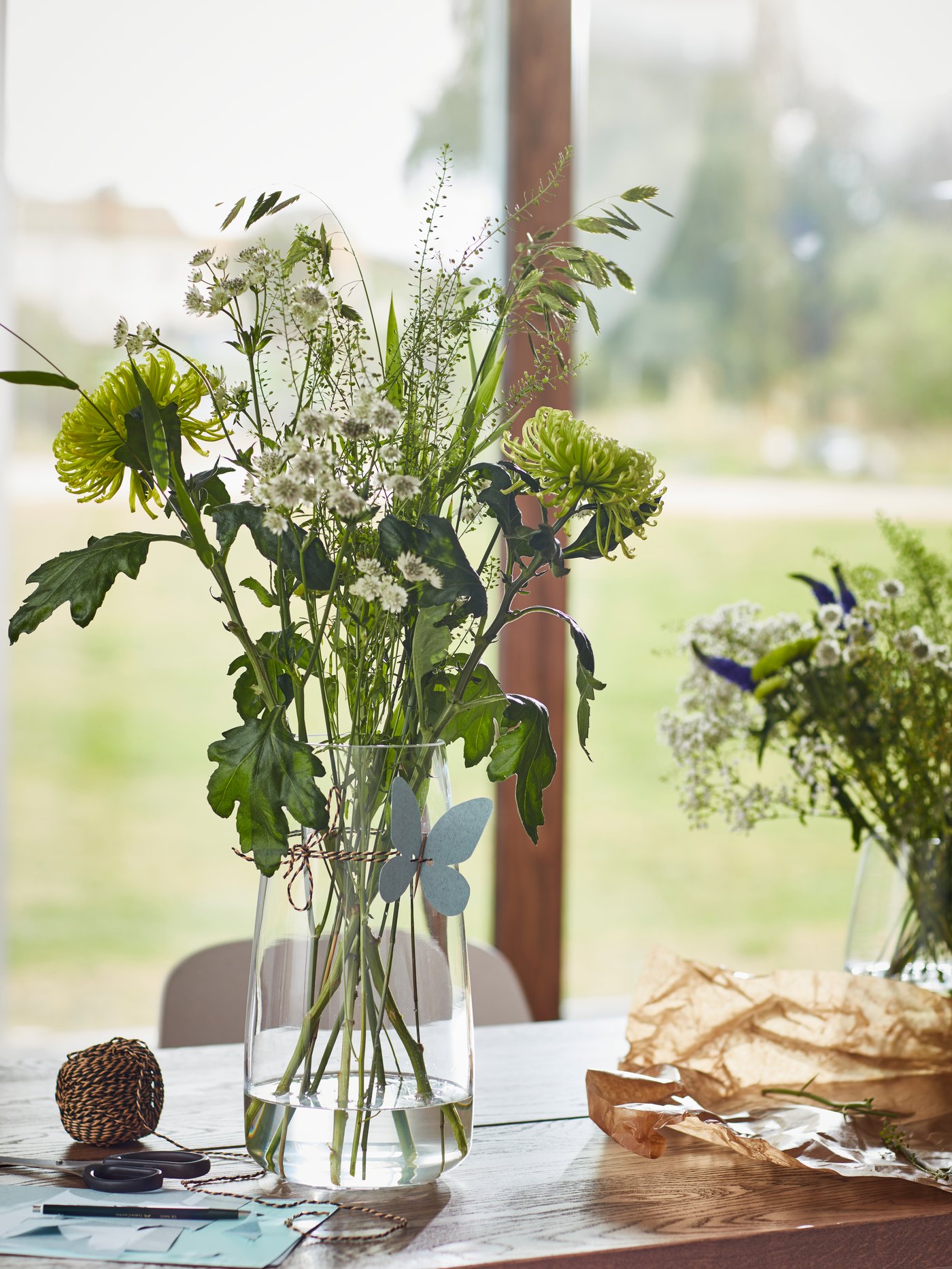 En buket af grønne blomster står i en vase på et bord. 