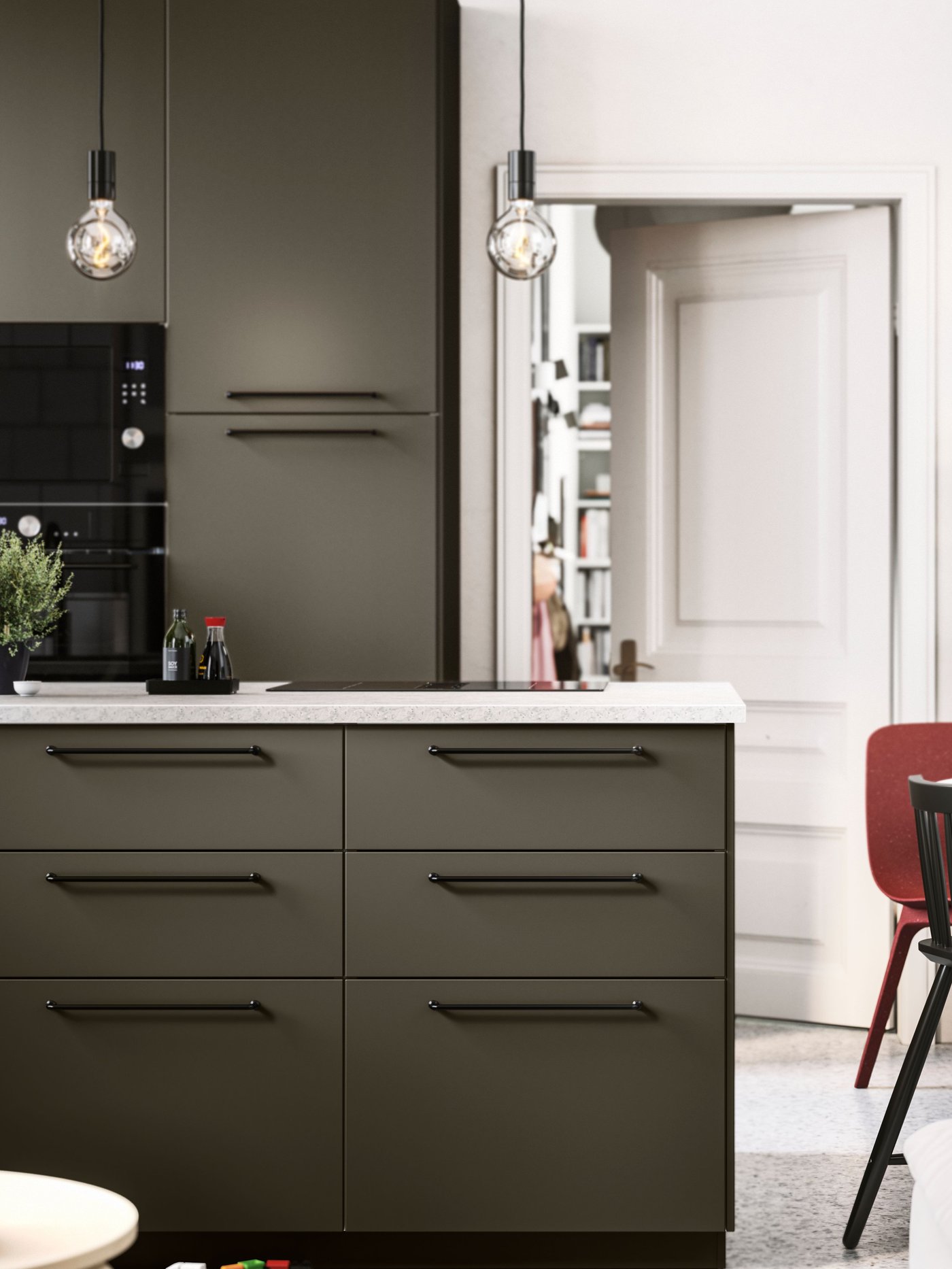 Et åbent køkken med brun-beige HAVSTORP køkkenfronter, sorte greb og hvidevarer, og en hvid bordplade.