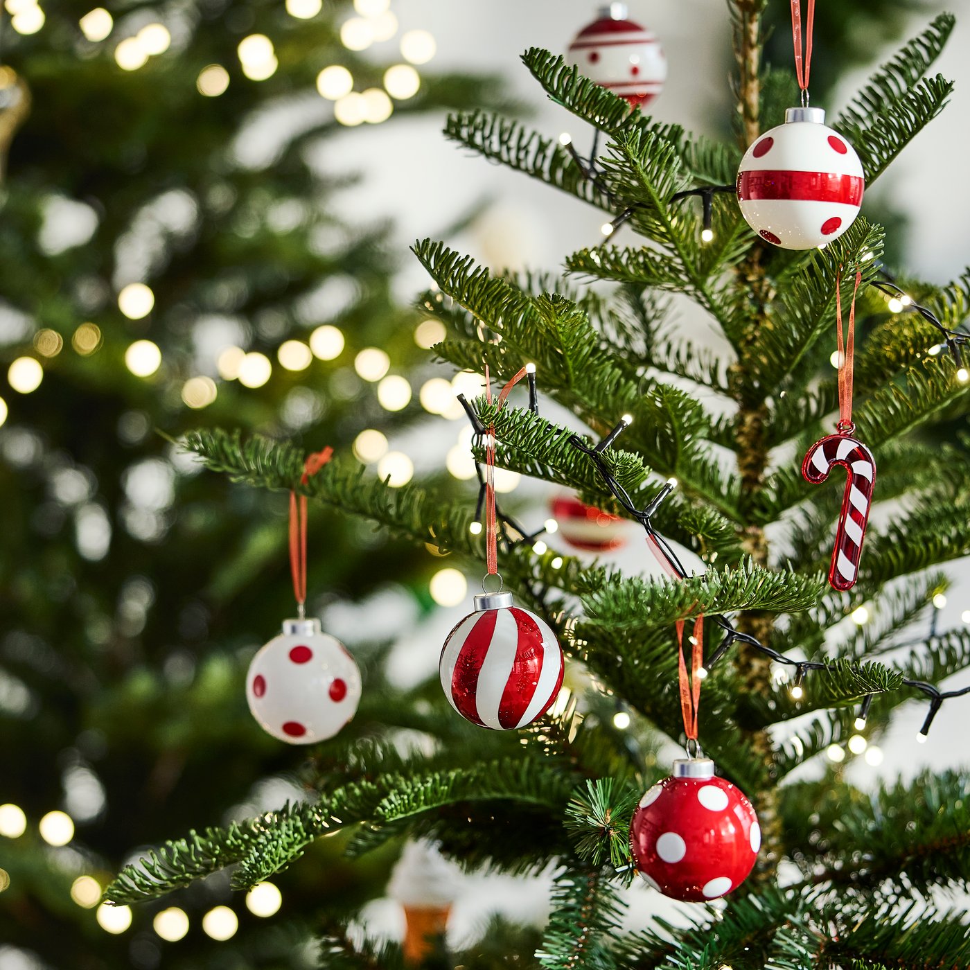 Julgran med röda och vita julkulor samt ljusslinga.