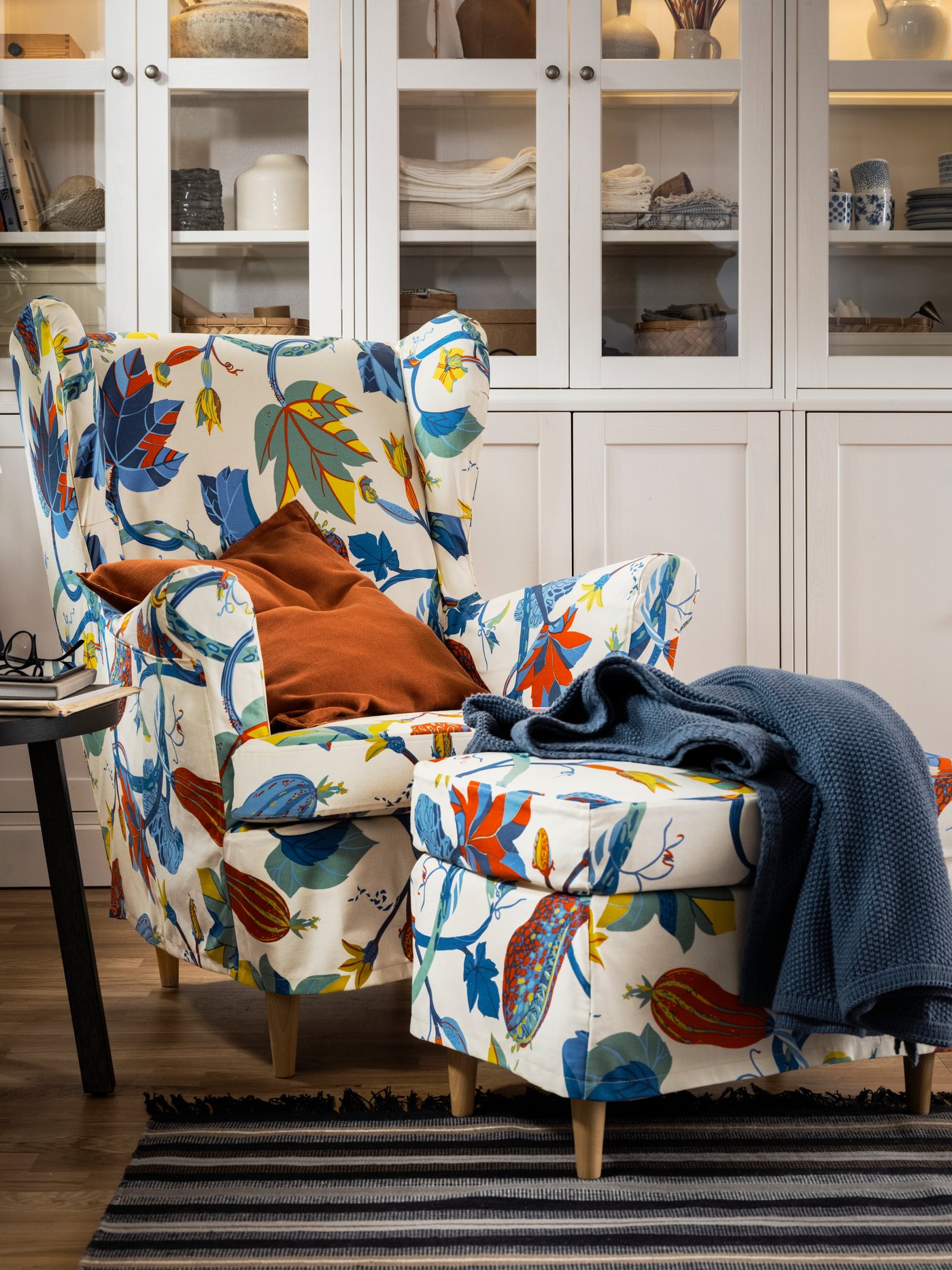 A STRANDMON wing chair and footstool, with Stigsbo slipcovers, stand in front of some HAVSTA storage combinations.
