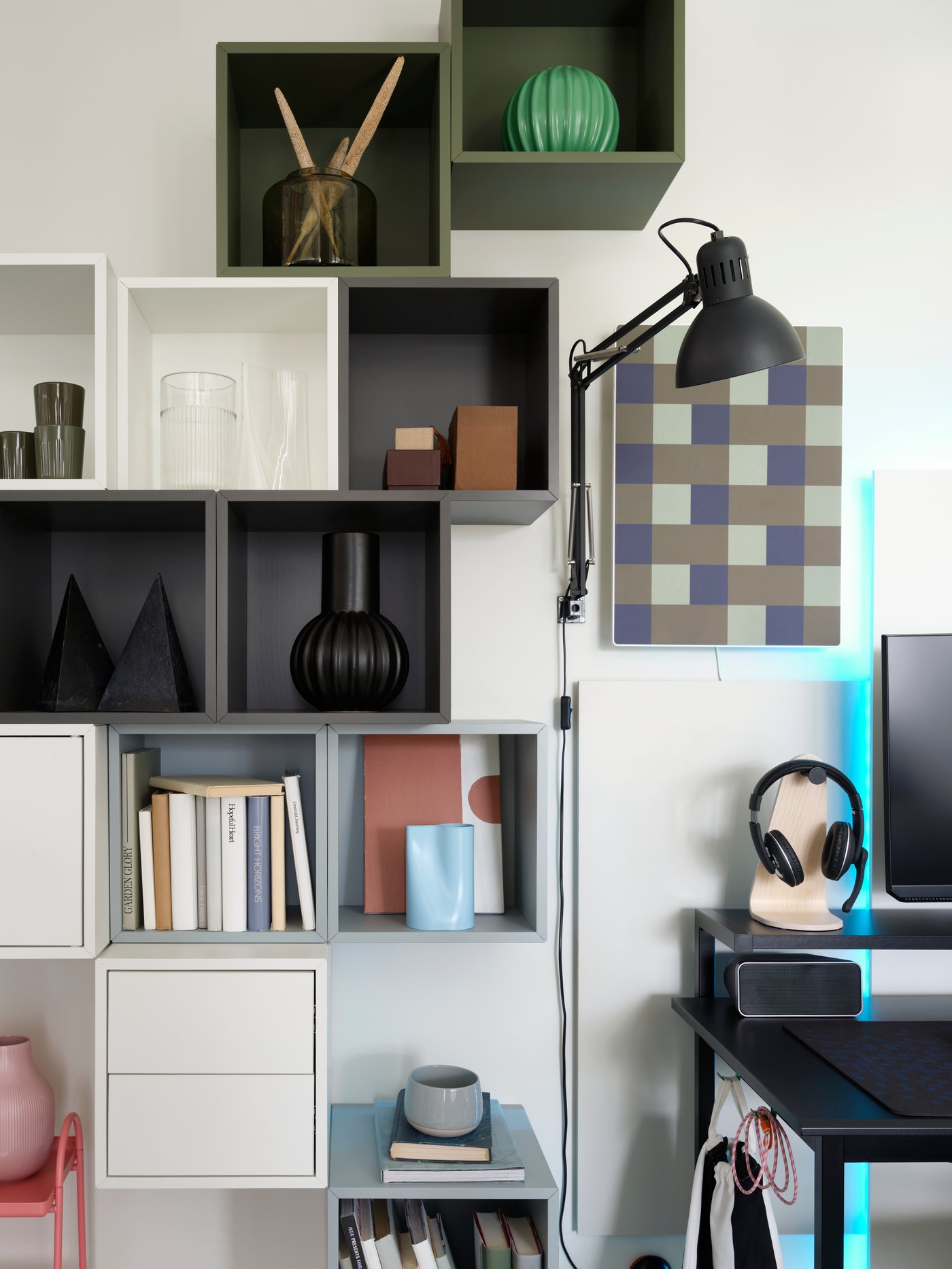 Neben einem Schreibtisch befindet sich eine asymmetrische Anordnung verschiedener EKET Wandregale, in denen moderne Dekoartikel und Bücher untergebracht sind.
