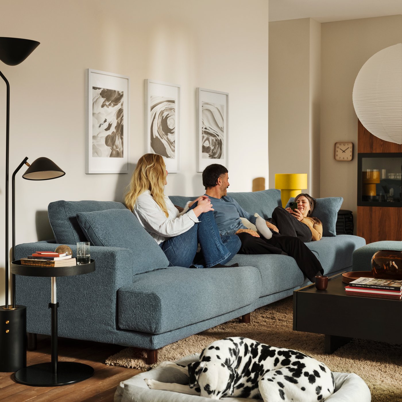 Trois personnes sont allongées sur un canapé modulable UPPÅKRA 4,5 places gris-bleu foncé, près d'une table basse TRANERED et d'une table d'appoint TRANERED.