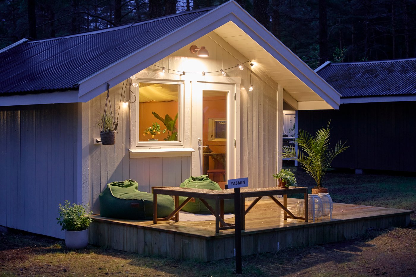 Ein kleines weißes Gartenhaus, das vorne dran beleuchtet ist.