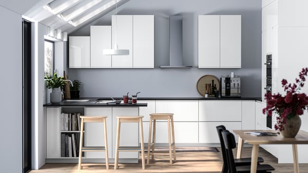 High-gloss white modern kitchen with a black worktop in a grey room with light wood flooring