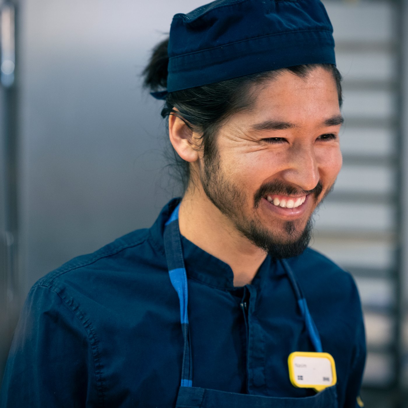 A smiling IKEA co-worker wearing blue workwear and a name badge.