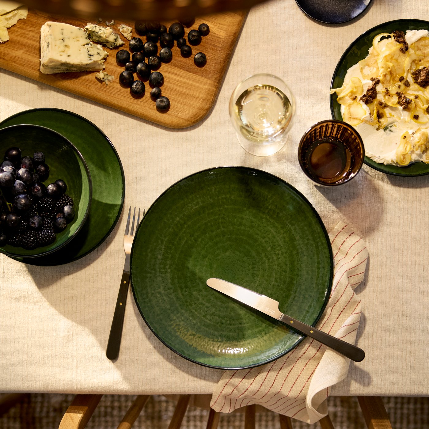 An eagle-eye’s view of a PELARKAKTUS plate in green, with a glossy finish and darker rim, next to a bowl and side plate.