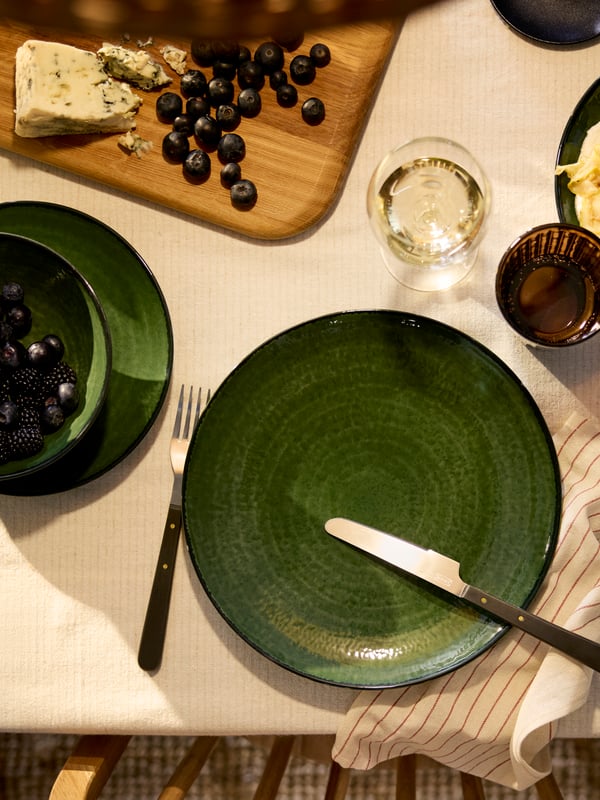 An eagle-eye’s view of a PELARKAKTUS plate in green, with a glossy finish and darker rim, next to a bowl and side plate.
