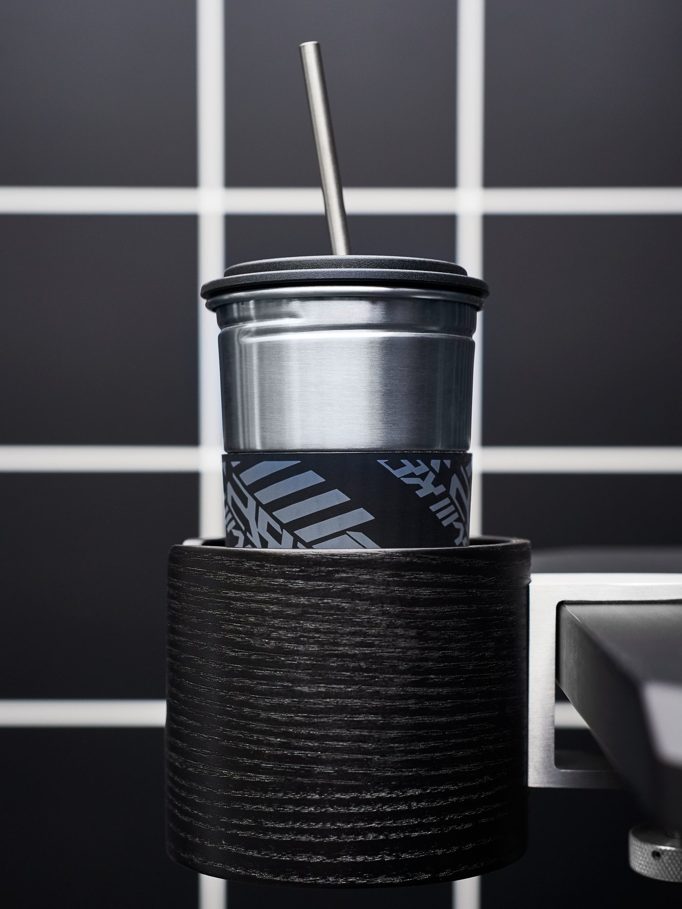 A LÅNESPELARE mug with lid and straw and a LÅNESPELARE mug holder against a black and white grid.
