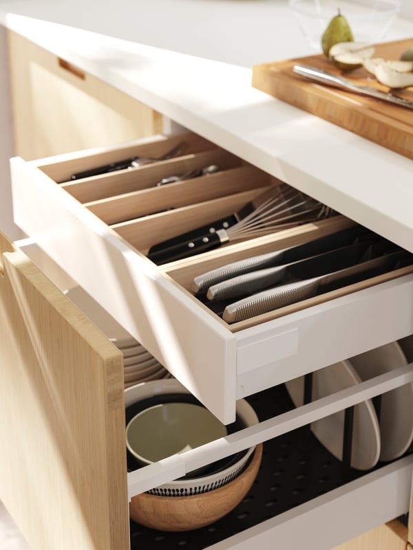 An open kitchen drawer with FRÖJERED front revealing UPPDATERA drawer accessories with cutlery and three IKEA 365+ knives.