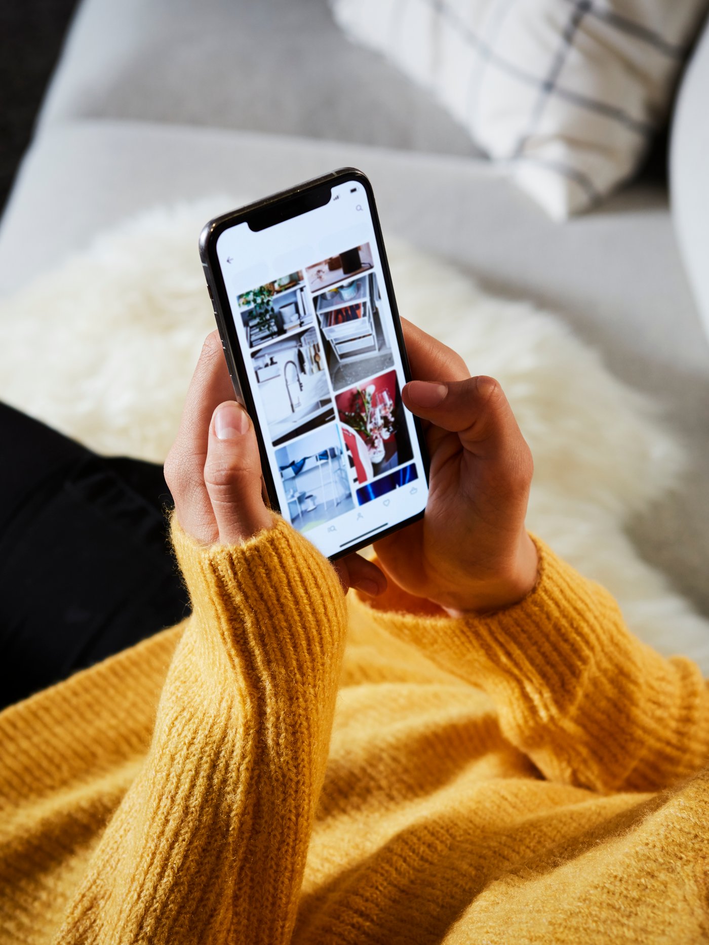 A woman wearing a yellow jumper using a mobile phone.
