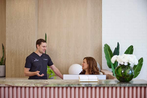 Two workers are talking behind a check-in counter in a spa business. 