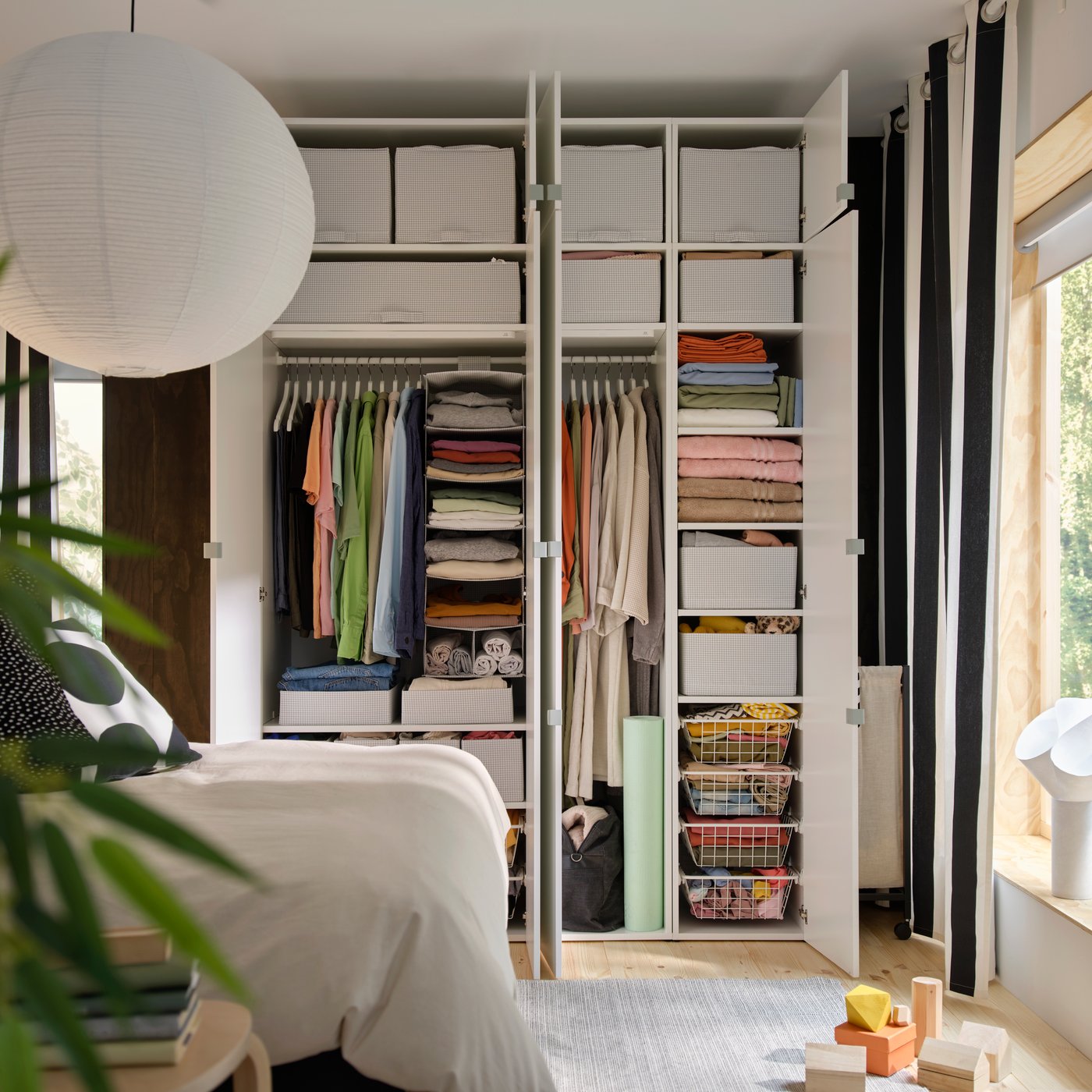 STUK förvaringslådor i vitt placerade på hyllor och i trådkorgar i en LASTARE garderobskombination i ett sovrum.