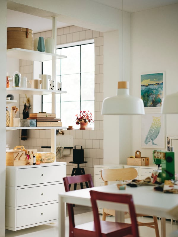 A white MELLTORP table with two red stained PINNTORP chairs and a RÖNNINGE chair below a white/birch BUNKEFLO pendant lamp.