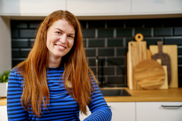 Kerstin Schön, Interieur Designerin bei IKEA in einer weißen IKEA Küche, mit schwarzem Fließenspiegel und einer Arbeitsplatte in Holzoptik.