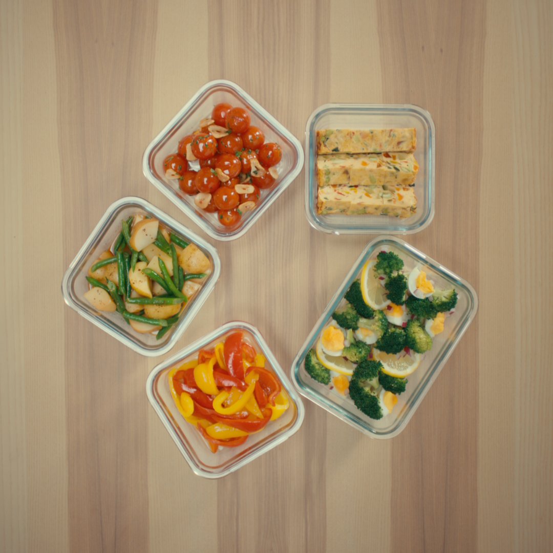 Meal prep vegetables in glass containers: tomatoes, broccoli, peppers