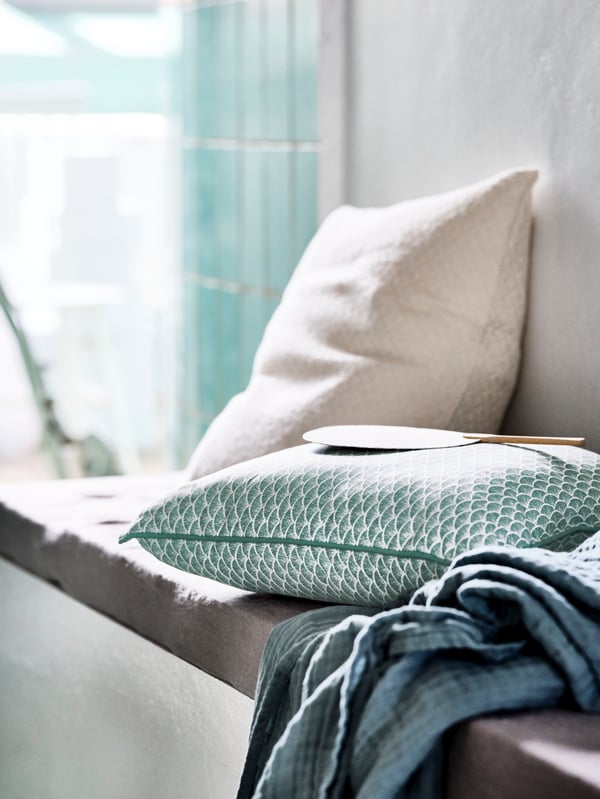 A grey DRÖMSK vase, other vases and other glass objects stand on a shelf in a RUDSTA glass-door cabinet.