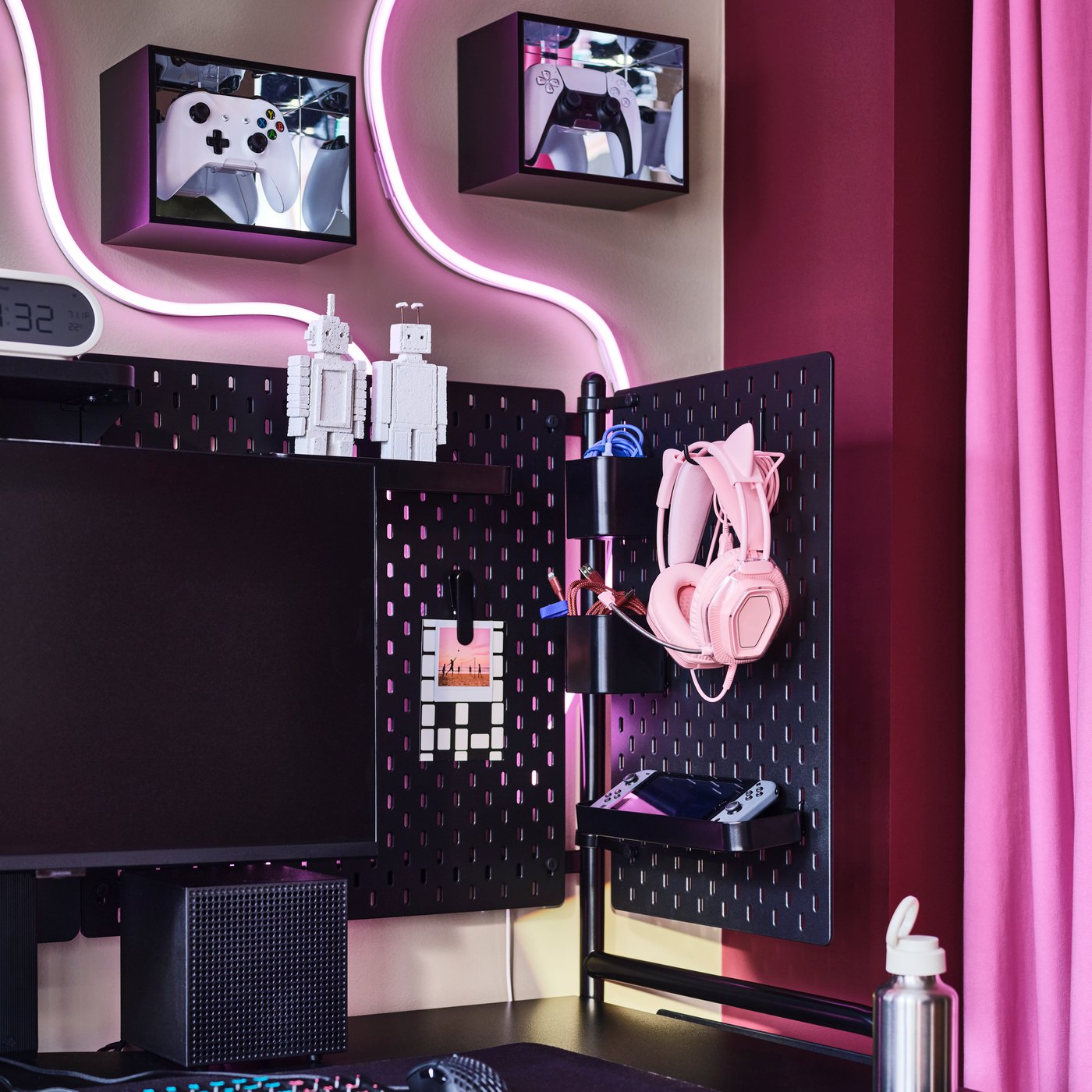 Ecke mit rosa Akzenten und YXSTABY Schaukästen für Gaming-Controller, die einen schwarzen FRÖSKELÅS Gamingschreibtisch einrahmen.