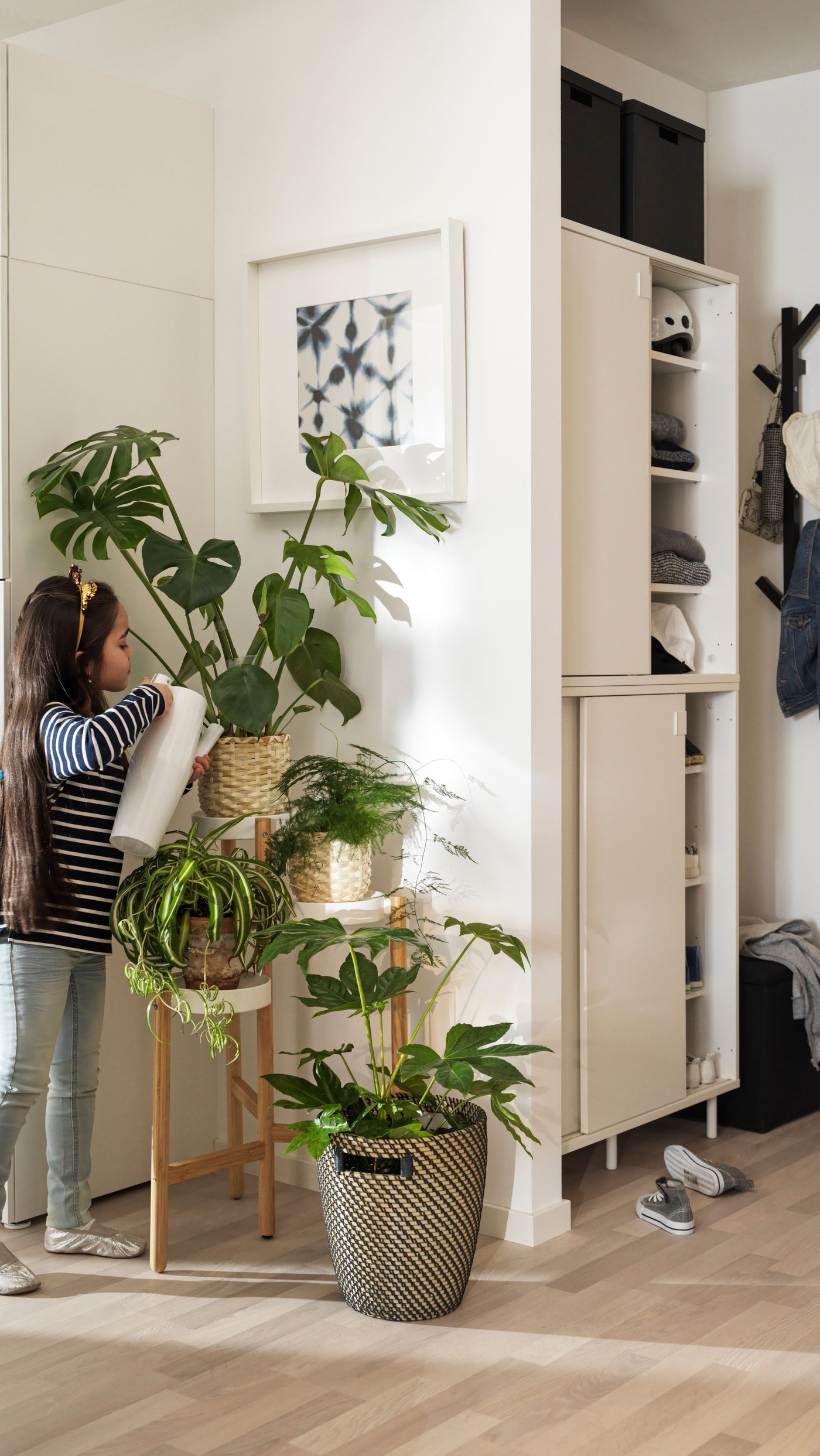 Young girl waters plants in the living room