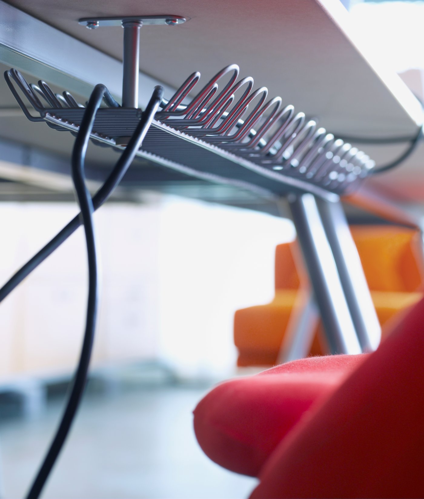 Two cables come out of the end of a SIGNUM cable trunking horizontal, which is attached under a desk.