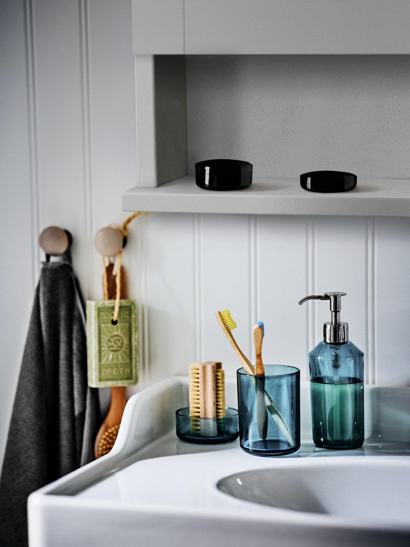 Rincón de baño con un juego de baño azul de 3 piezas de cristal colocado sobre un lavabo blanco con 2 cajones.