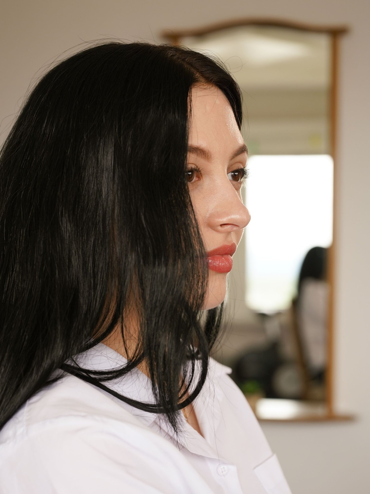 Side portrait of a girl standing in focus at a doorway.