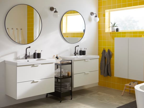 A bathroom with two sinks and yellow tiles on the wall.