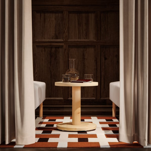 A close-up of a break room with two LILLEHEM sofas, a pine sidetable in the centre, positioned on a geometric patterned rug.