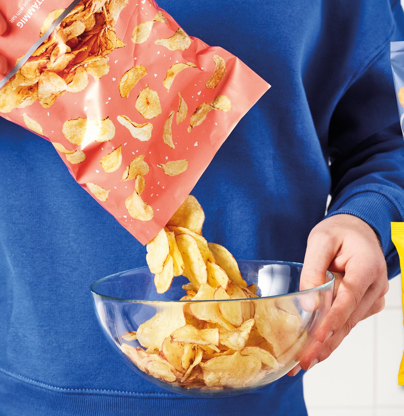 Eine Person kippt eine Packung Chips in eine Schüssel.