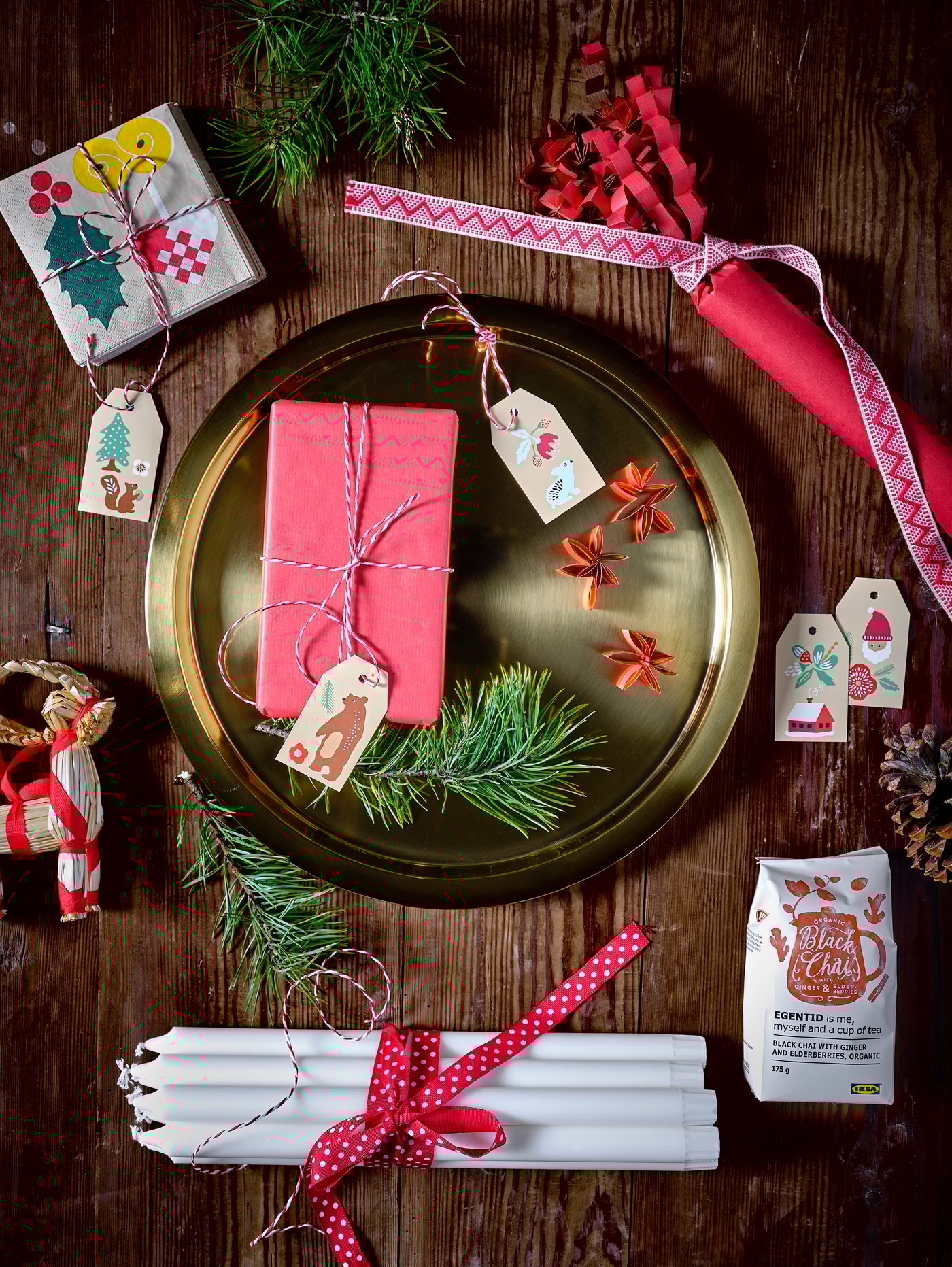 Gift ideas on a golden tray, with tall white dinner candles and various wrapping paper for the holidays.