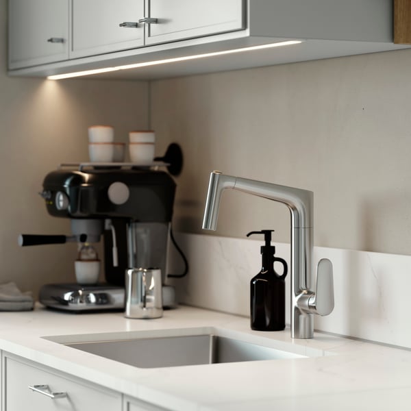 MAJSJÖN kitchen mixer tap pull out with spray, placed above a sink with white worktop and black soap dispenser.