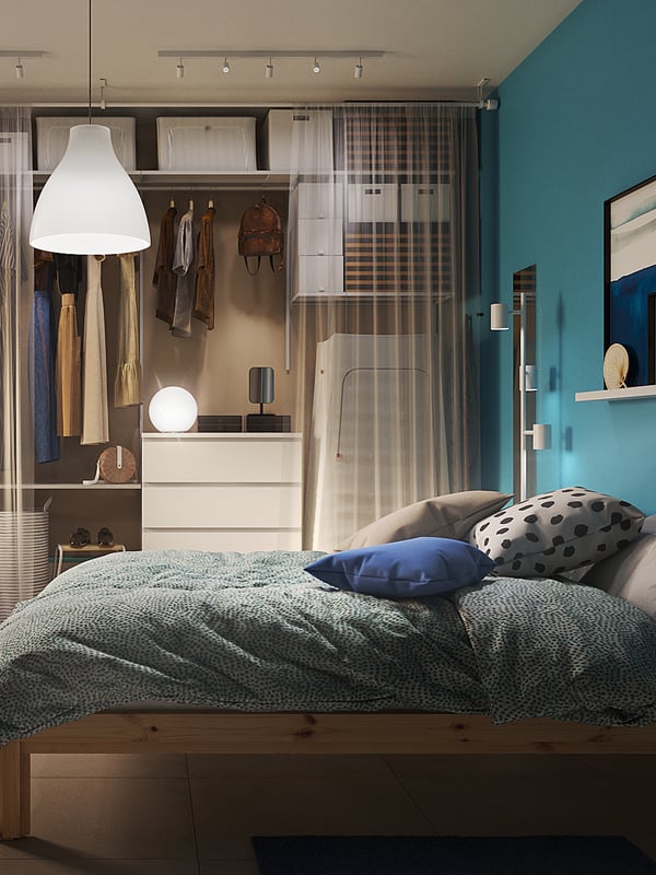 Luminosa camera da letto con un sommier FINNSNES grigio, biancheria colorata e grande guardaroba PAX/FORSAND.